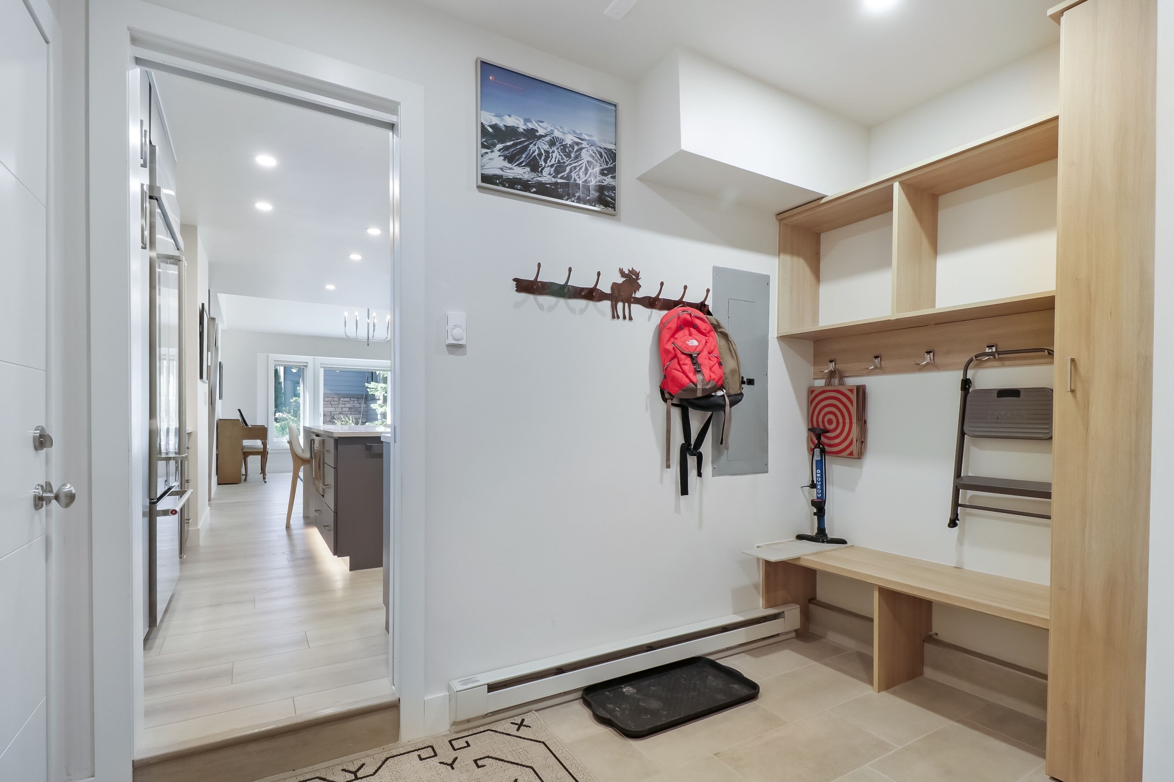 Una cocina moderna con armarios de madera, una mochila roja colgada de un perchero y un objetivo en la pared.