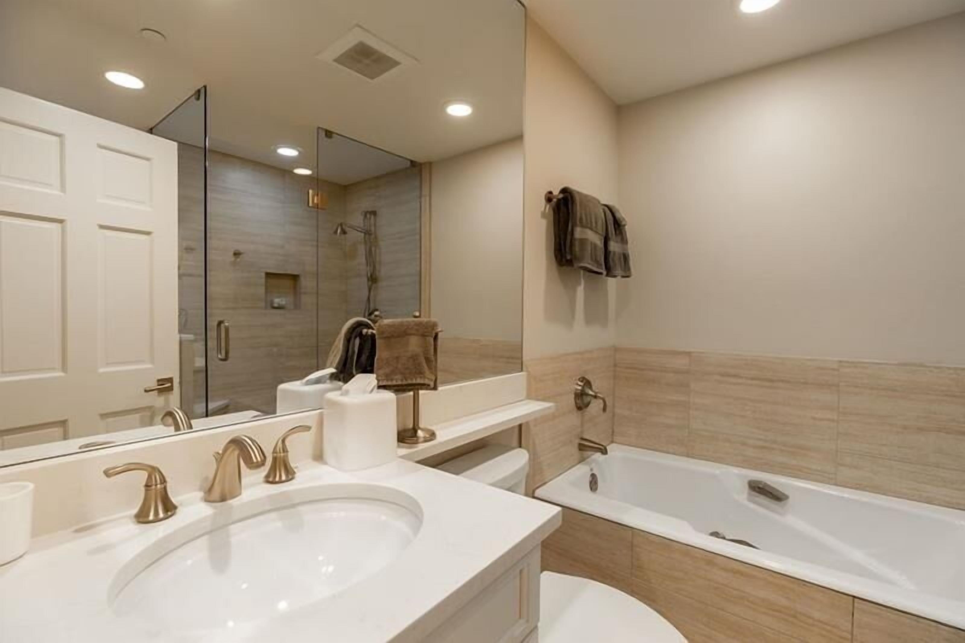 Une salle de bain moderne avec un grand lavabo, une baignoire et un miroir.