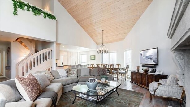 A spacious living room with a high ceiling, a staircase, a dining area, and a television.