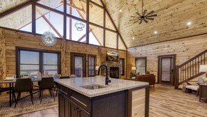 A spacious cabin interior with a large kitchen island, dining area, and a cozy seating space. - Er29 - Pop's Perch 2 Bedroom Cabin by RedAwning (Pigeon Forge)