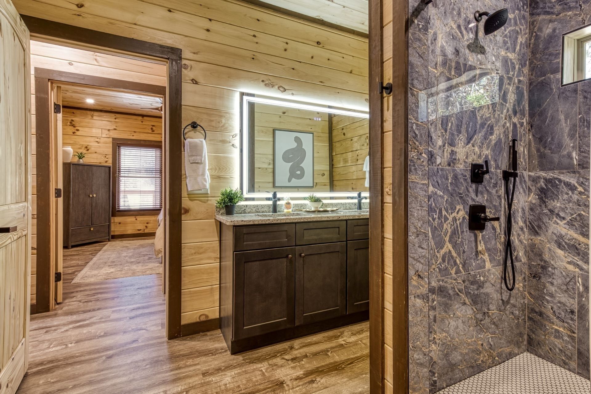 Un interior de madera con un baño que cuenta con ducha de mármol, armarios de madera y un espejo grande.