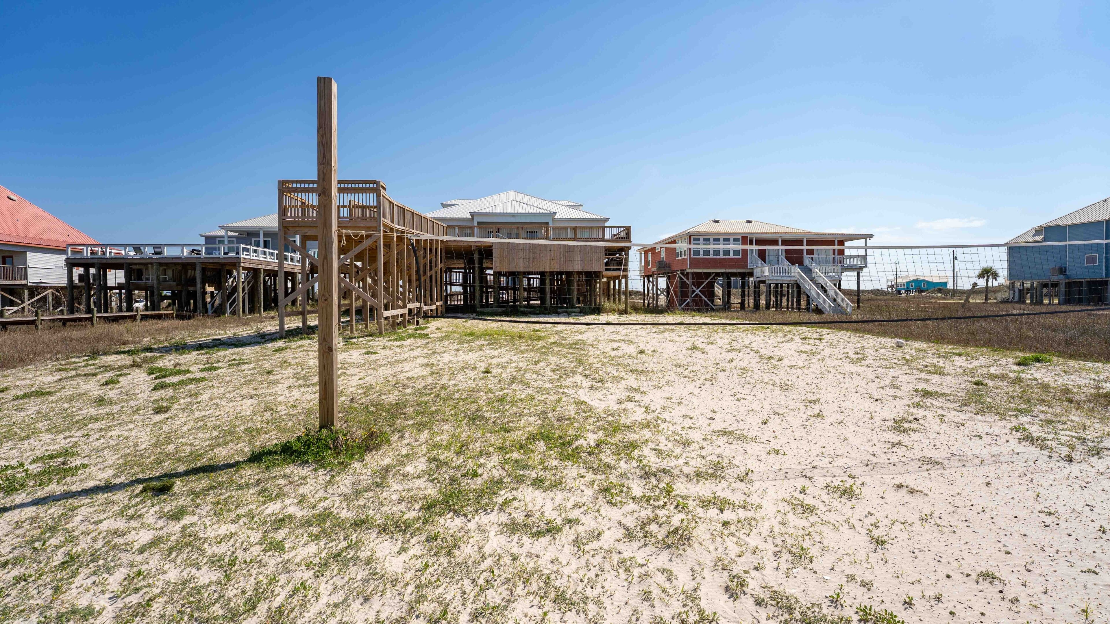 Una propiedad frente a la playa con estructuras de madera elevadas, una playa arenosa y cielo despejado.