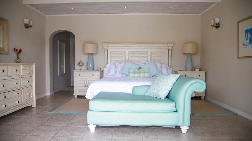 A bedroom with a bed, a light blue sofa, a dresser, and two nightstands with lamps.