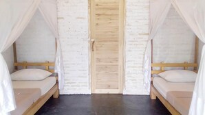 Ein Zimmer mit zwei Holzbetten, weißer Bettwäsche und einer weißen Ziegelwand.