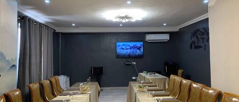 Una sala conferenze con un lungo tavolo, poltrone in pelle, una televisione a schermo piatto e un condizionatore d'aria.