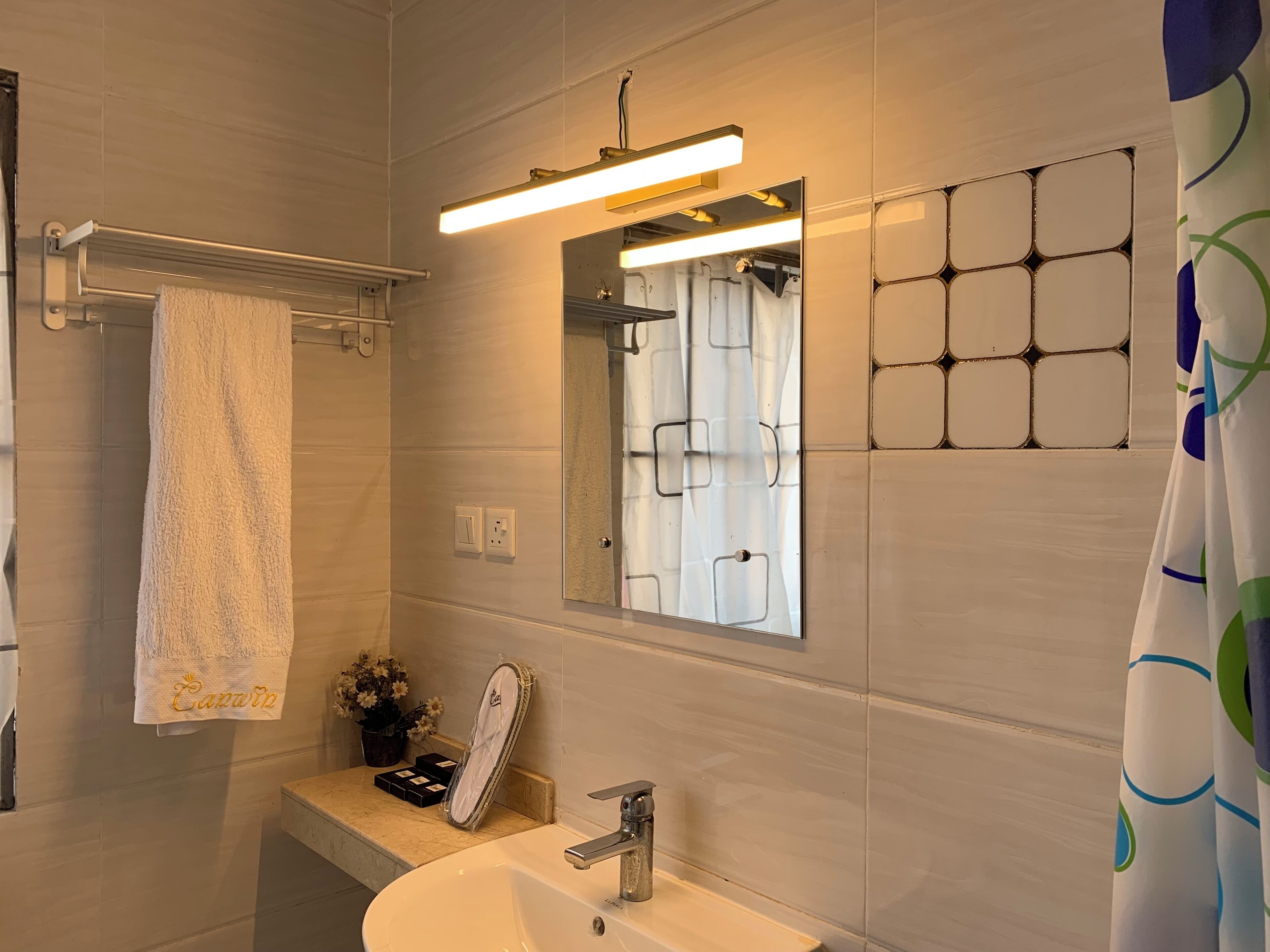 A bathroom with a sink, mirror, towel rack, and a shower curtain.