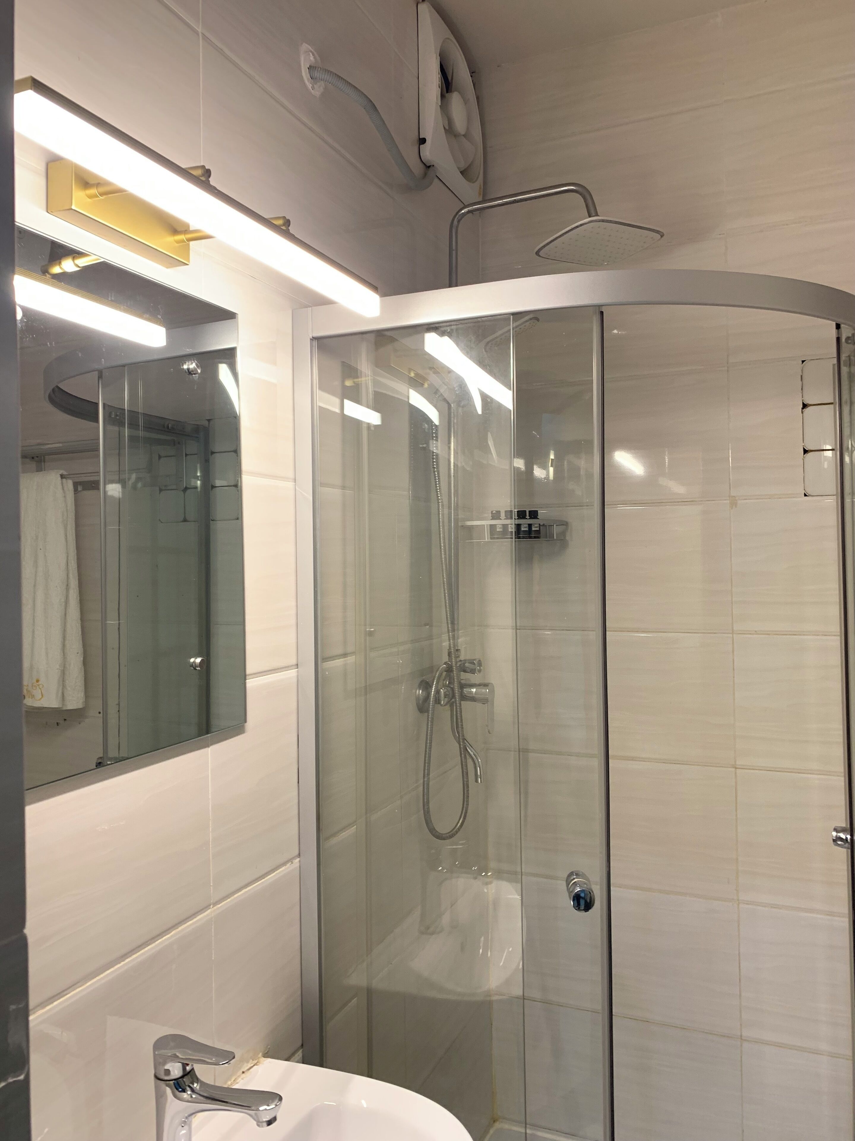 Une salle de bain moderne avec une douche à parois de verre, un lavabo blanc et un miroir au-dessus du lavabo.