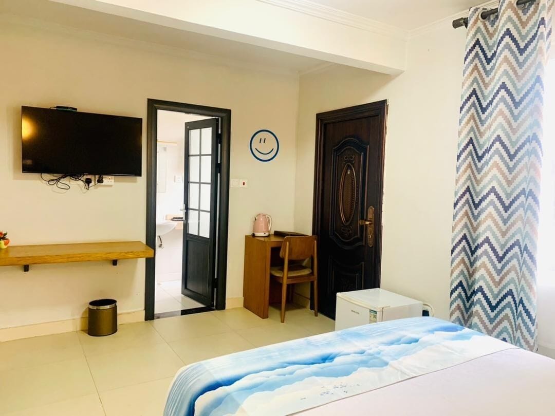 Une chambre à coucher avec un lit, un bureau, une chaise, une télévision et une porte.