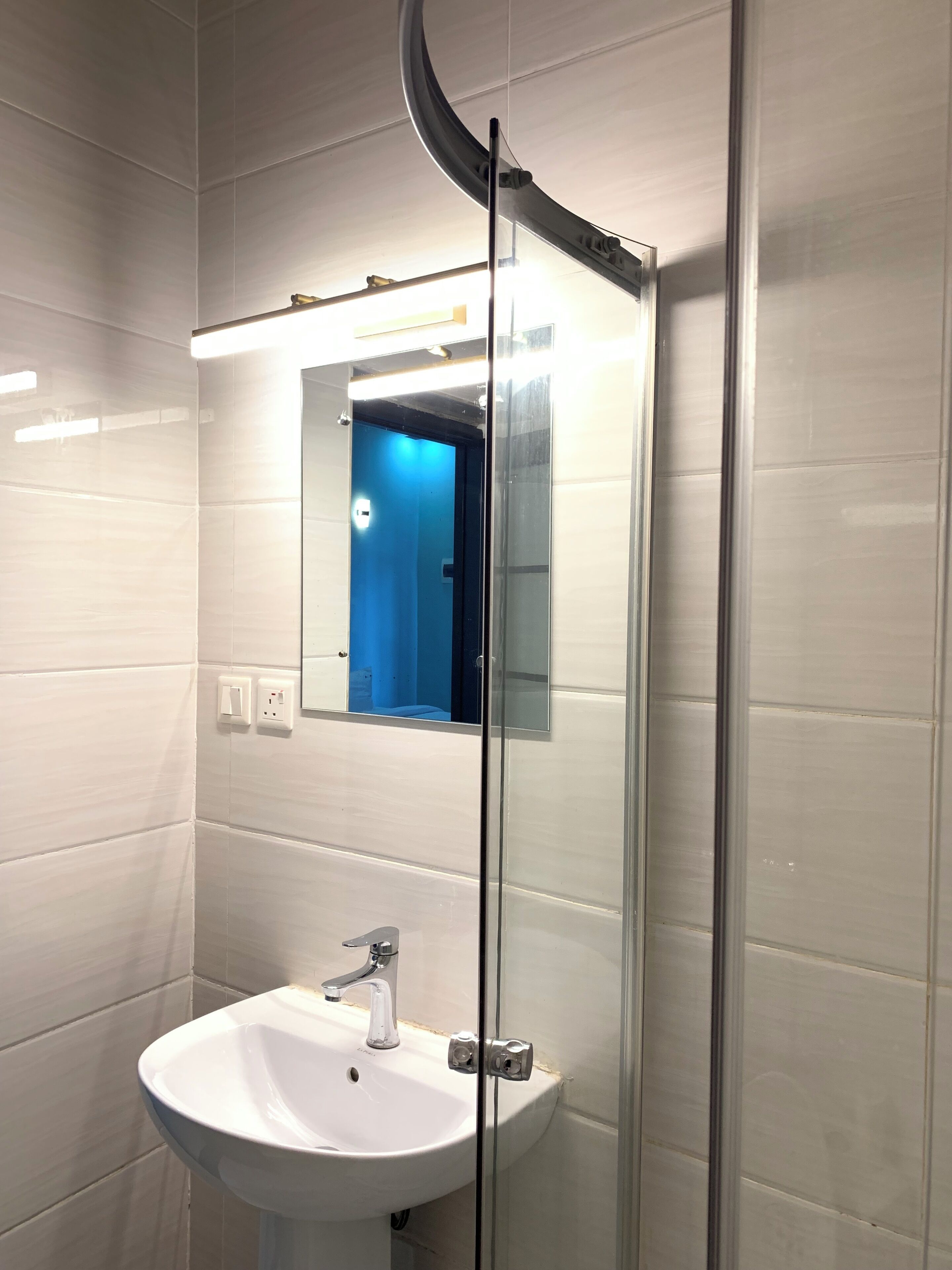 A bathroom with a white sink, a mirror, and a glass shower enclosure.