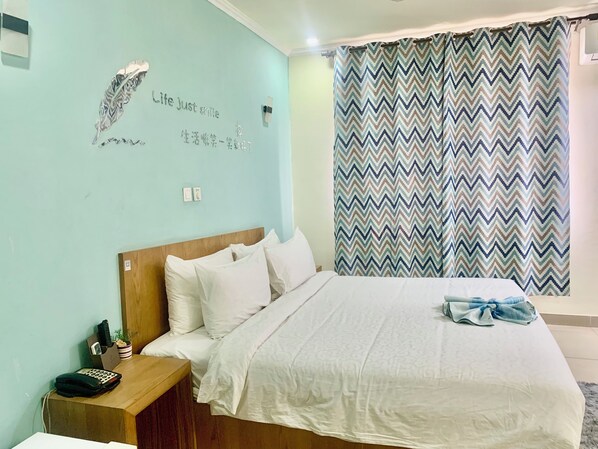 Un dormitorio con cama, mesita de noche, lámpara de pared y cortina estampada.