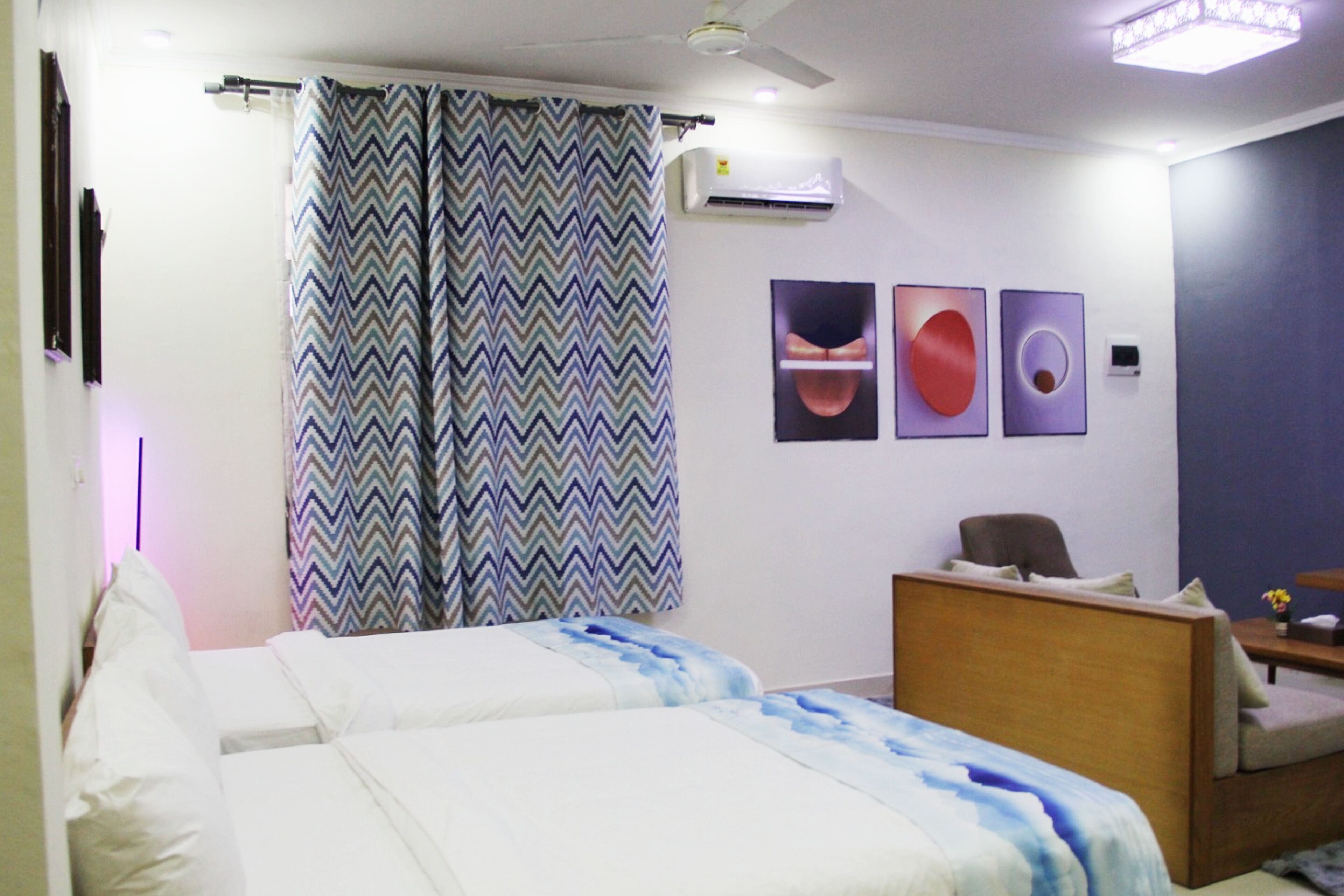 A hotel room with a bed, a desk, a chair, and a ceiling fan.