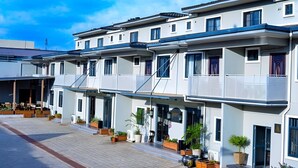 A modern hotel with multiple balconies, a covered outdoor seating area, and potted plants. - Canwin Hotel (Accra)