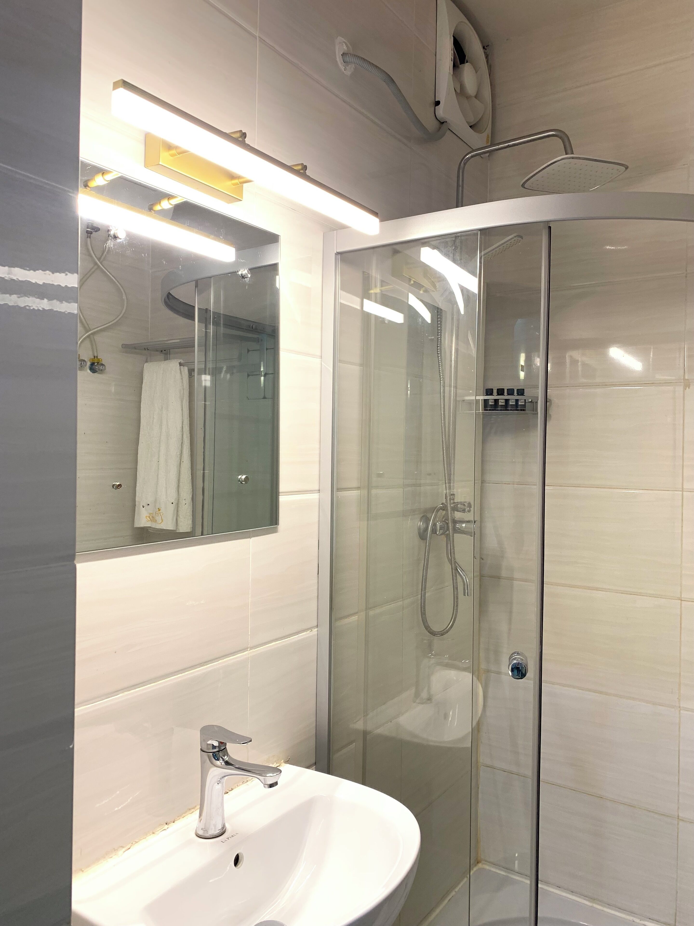 A modern bathroom with a glass-enclosed shower, a white sink, and a mirror above the sink.