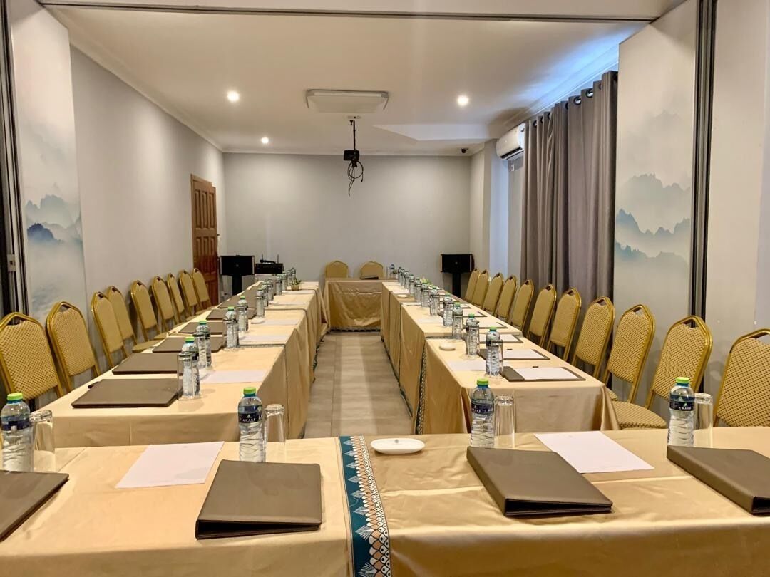 A conference room with long tables, chairs, water bottles, and laptops.