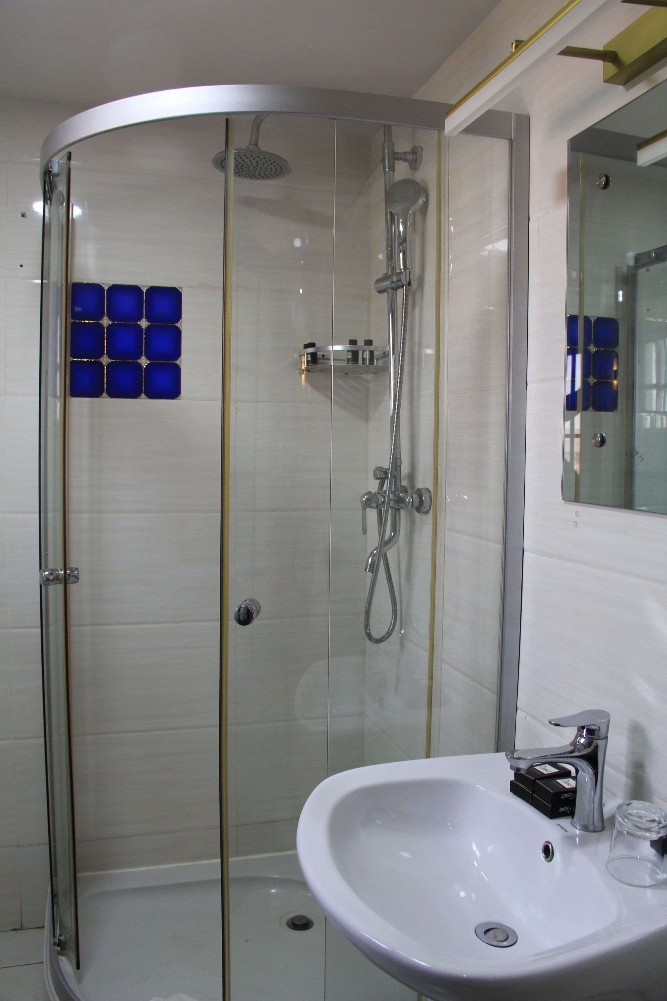 A modern bathroom with a glass-enclosed shower, a white sink, and a mirror above it.