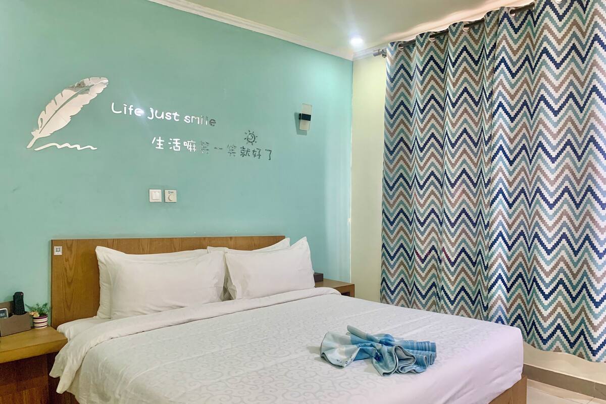 A neatly made bed with white linens and a folded towel on the bed.
