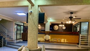 A hotel lobby with a reception desk, a staircase, and a seating area with cushions. - Canwin Hotel (Accra)