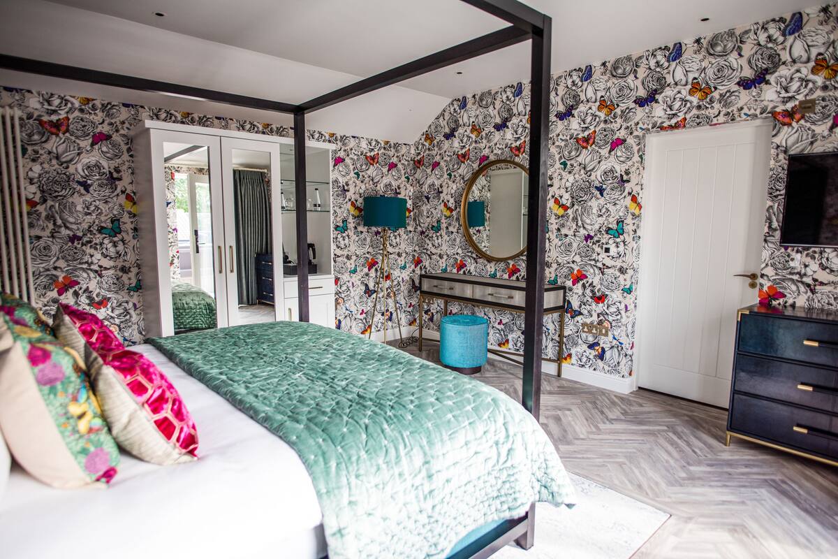 A bedroom with a bed, a wardrobe, a mirror, and a dresser.