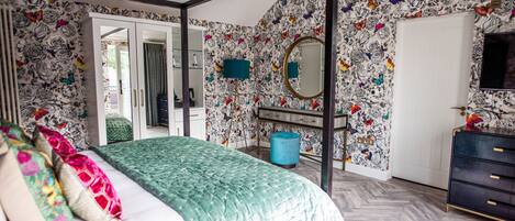 A bedroom with a bed, a wardrobe, a mirror, and a dresser.