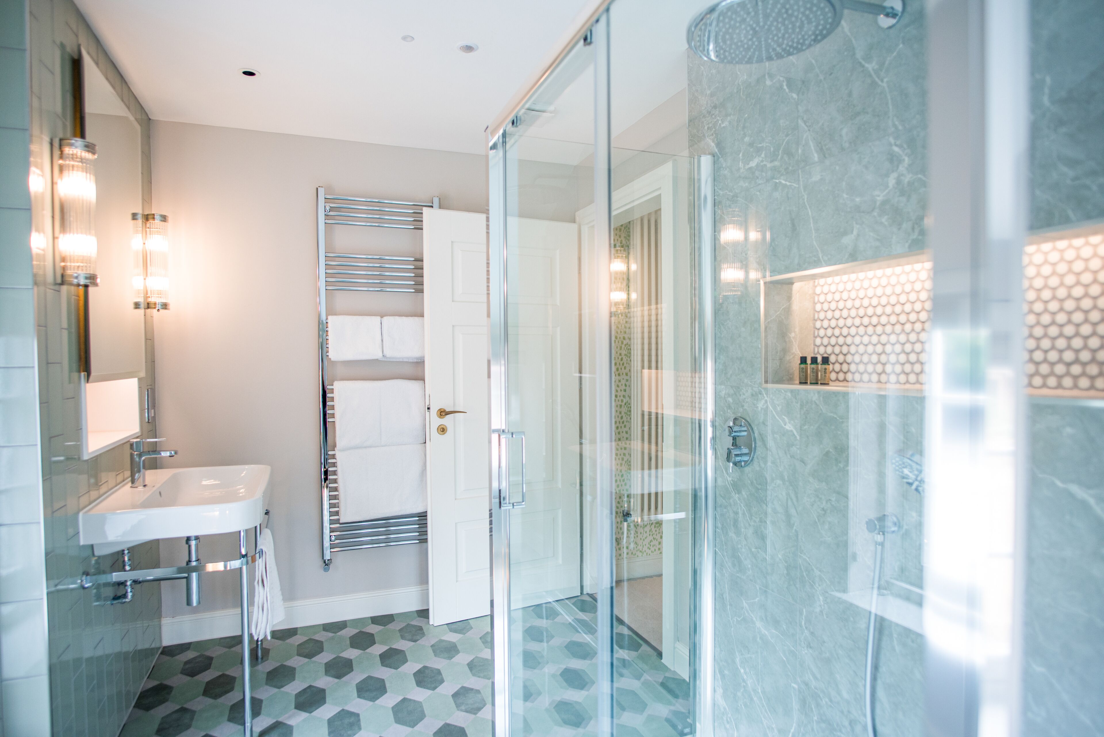 Une salle de bain moderne avec une douche à parois de verre, un lavabo blanc et un porte-serviettes.