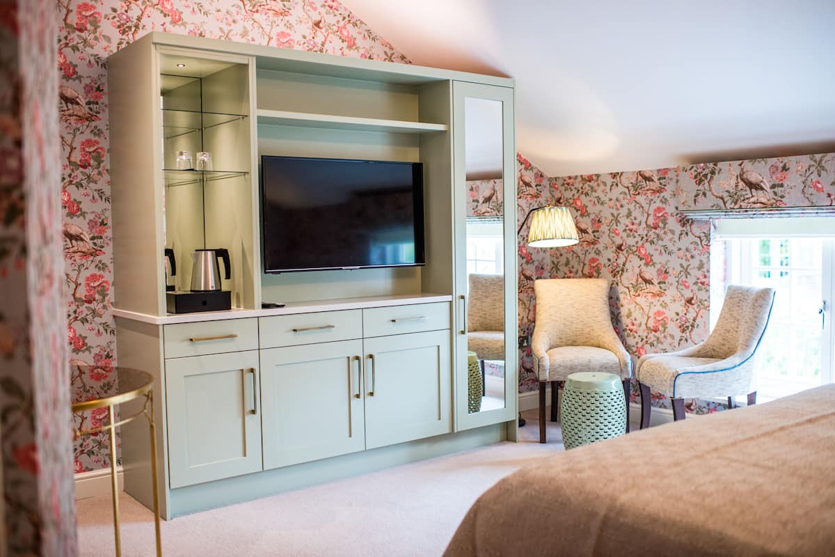 A bedroom with a TV, two chairs, a small table, and a cabinet.