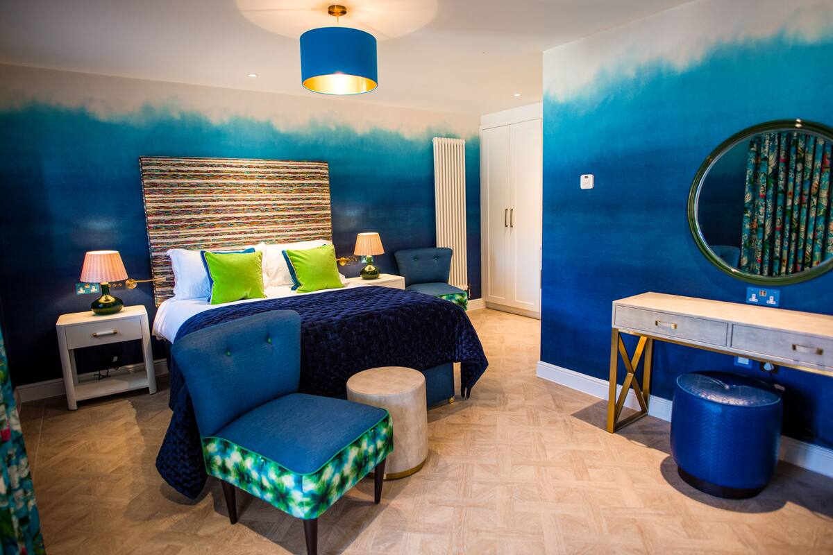 A bedroom with a bed, bedside tables, a chair, a dresser, and a mirror.