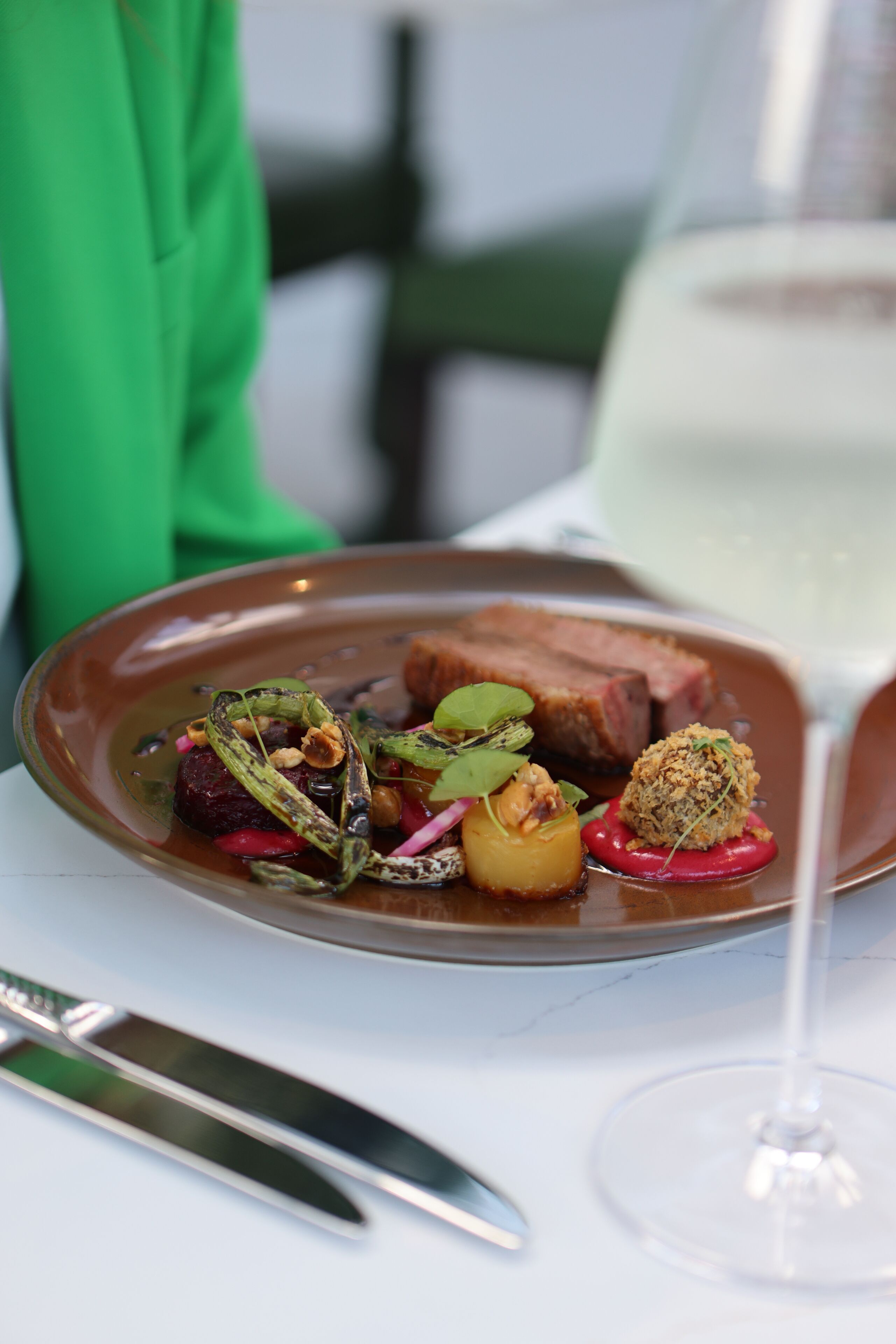 A plate of food with a glass of white wine on a table.