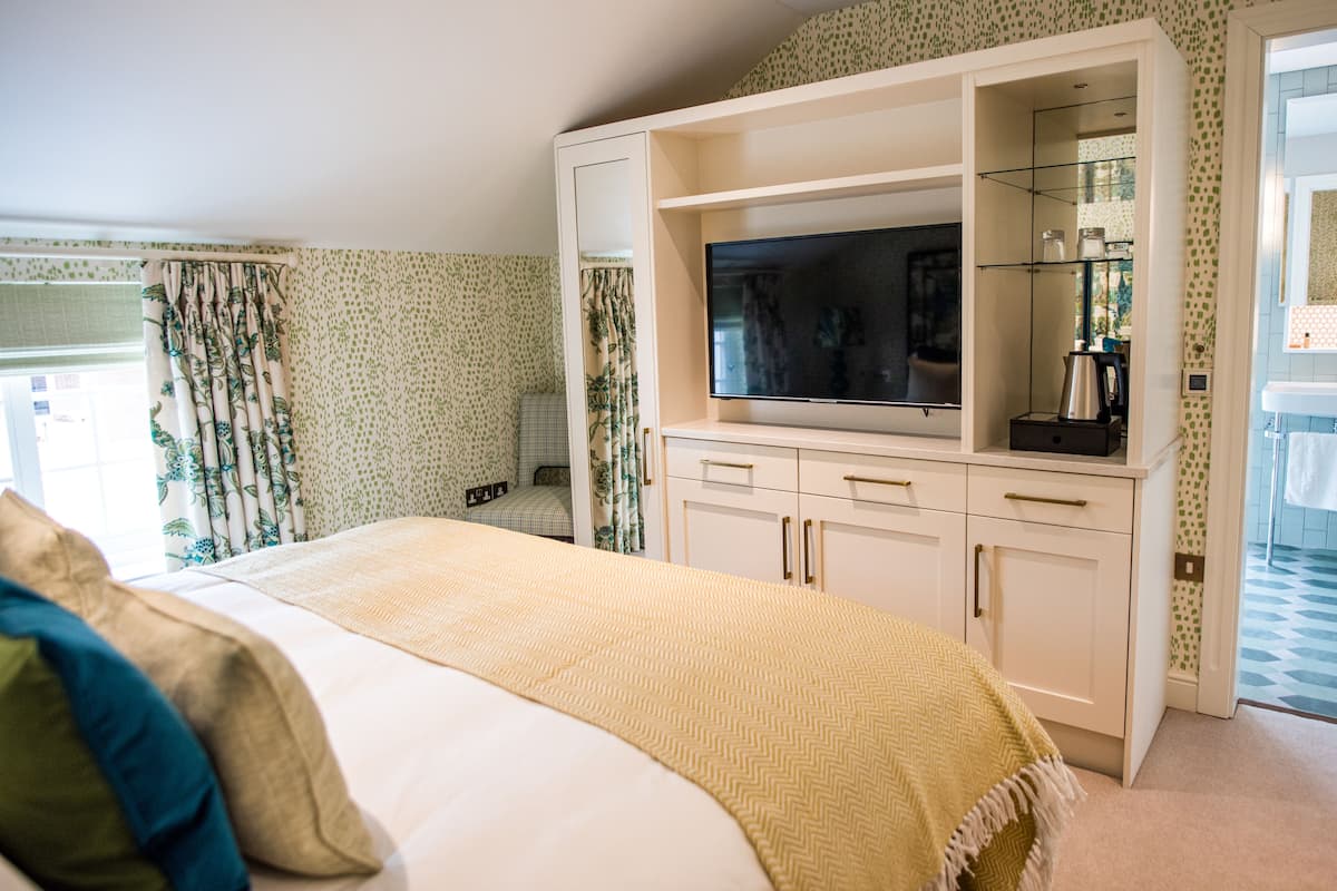 A bedroom with a bed, a TV, a coffee maker, and a wardrobe.