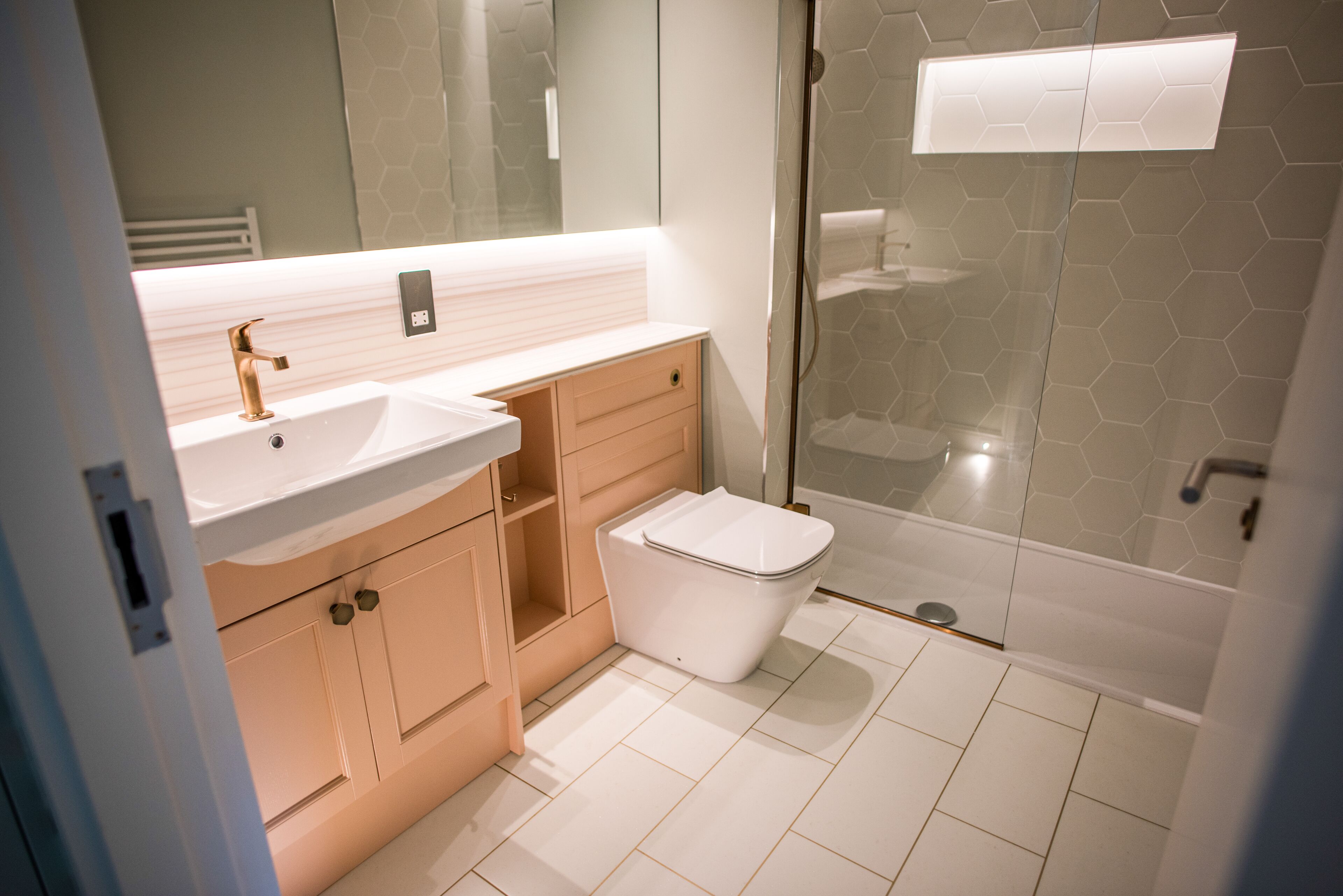Ein modernes Badezimmer mit einem weißen Waschbecken, einer Toilette und einer Dusche in einer Glaswand.