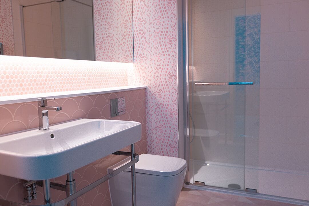 A bathroom with a white sink, a mirror, a shower with a glass door, and patterned walls.