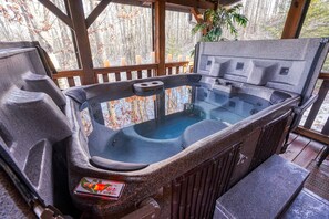 A hot tub with a control panel, surrounded by wooden deck and a view of trees. - NEW 2024 Update| Hot Tub | Near Trails| Game Room| Firepit| Secluded 8 acres (Logan)