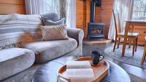 A cozy cabin interior with a sofa, a wooden table with a tray, a book, and a black mug.