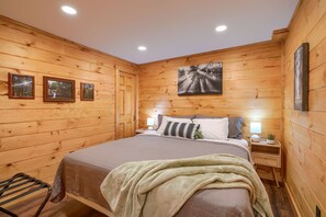 Una habitación con paneles de madera, una cama, mesitas de noche y cuadros en las paredes.