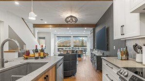 Een moderne keuken met een groot schiereiland, roestvrijstalen apparatuur en uitzicht op bergen door grote ramen.