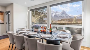 Een eetruimte met een tafel voor zes personen, grote ramen met uitzicht op de bergen, en een modern interieur.