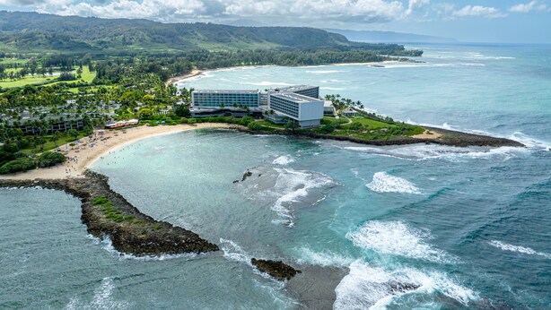 A coastal resort with a beach, ocean views, and a large building with multiple floors.
