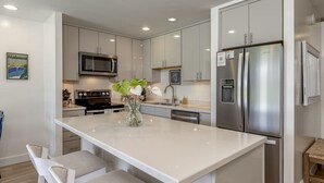 A modern kitchen with stainless steel appliances, a central island with seating, and a microwave above the stove.
