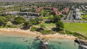 Vista aérea de un pueblo costero con playa, edificios residenciales y un gran complejo hotelero.