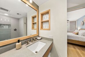 Une salle de bain moderne avec un grand miroir, un lavabo et une douche.