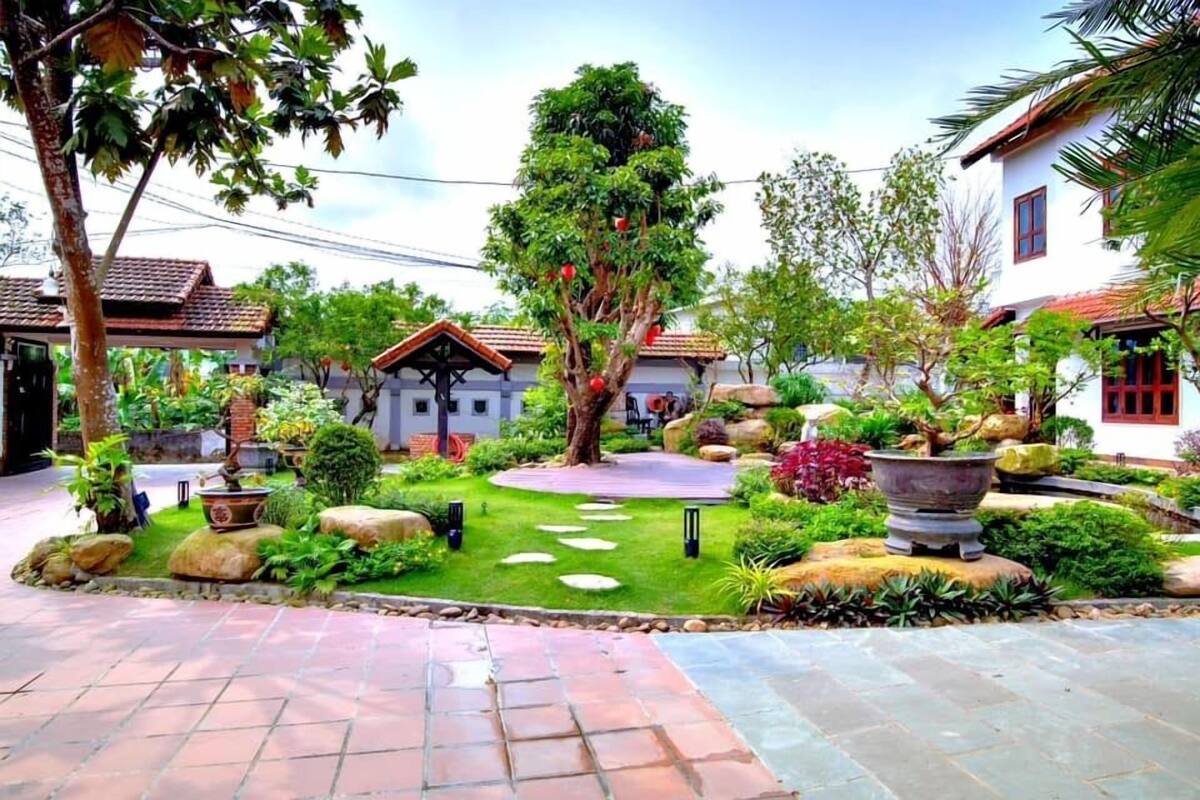A well-maintained garden with a central circular stone pathway, surrounded by various plants and trees.
