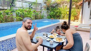 Una mesa de comedor con platos de comida y una piscina al fondo.