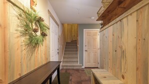 A hallway with wooden walls, a bench, a staircase, and a door. - Waterside West E206 Fraser 2 bedroom open floor plan & lots of amenities (Fraser)