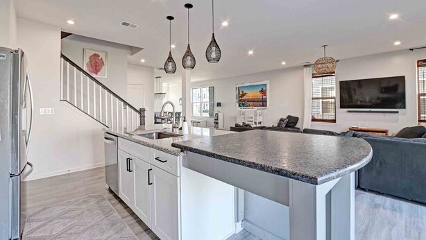 A modern kitchen with a central island, white cabinetry, and pendant lighting.