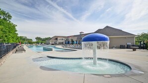 A swimming pool area with multiple pools, a water feature, and a building with a blue dome roof in the background.