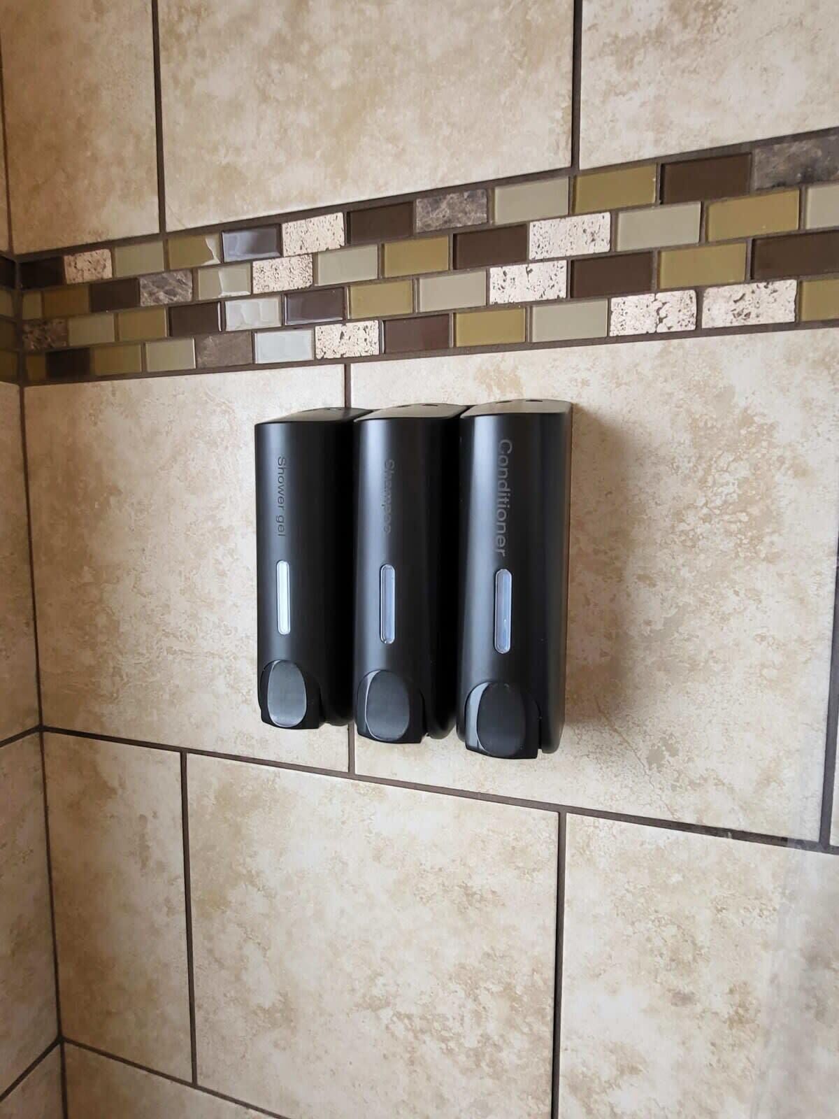 Ein an der Wand montierter Handtrockner mit Bedienfeld, vor einer mit Mosaikbordüre versehenen Fliesenwand.