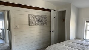 Une chambre avec un grand lit, un placard aux portes coulissantes et une œuvre d’art accrochée au mur.