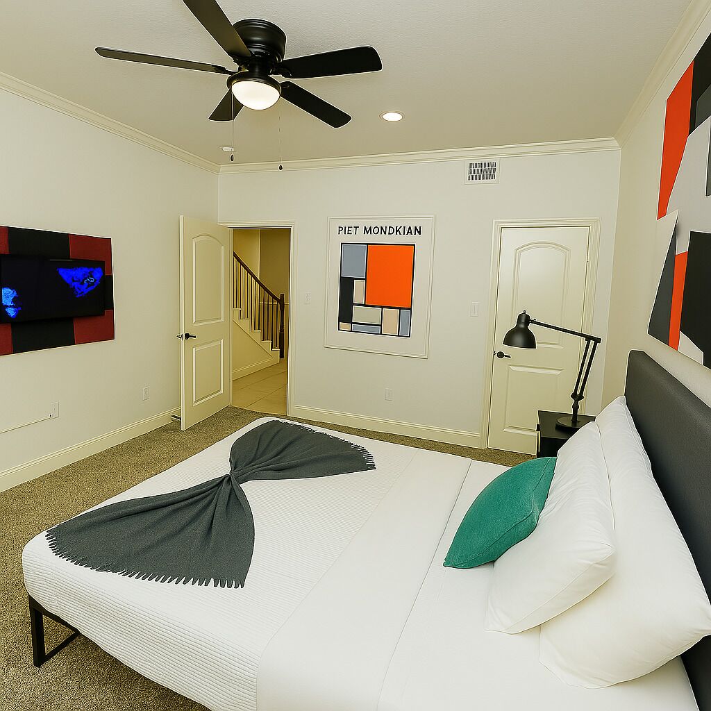 A hotel room with a bed, a ceiling fan, a TV mounted on the wall, and a poster on the wall.