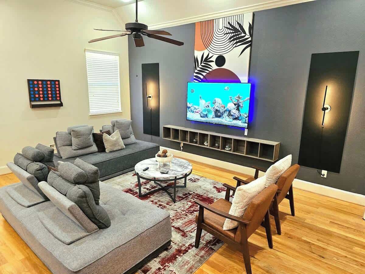A modern living room with a grey sectional sofa, a coffee table, and a TV mounted on the wall.