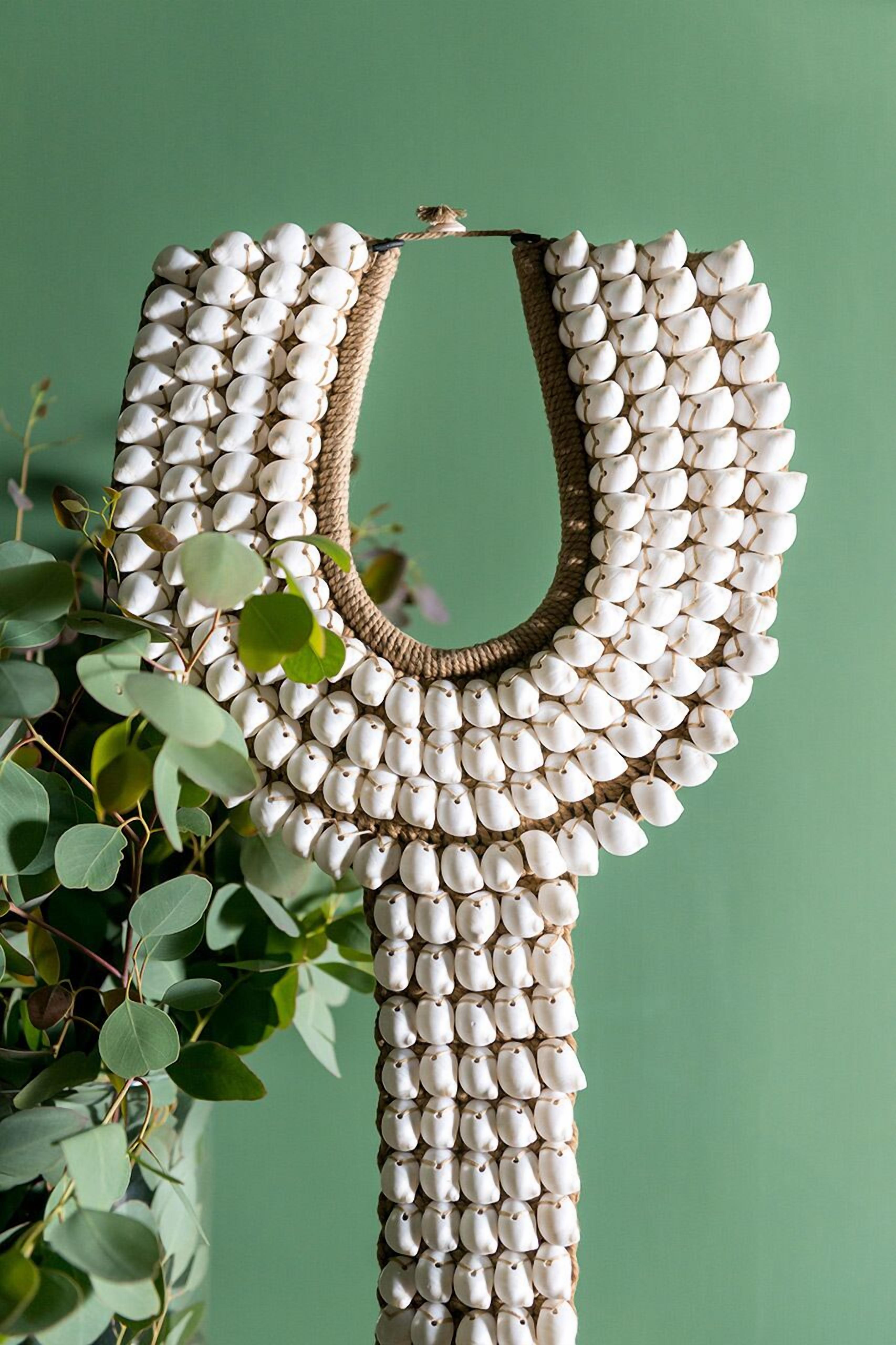A necklace made of white beads and a woven base, set against a green background.