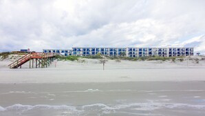 A beachfront hotel with a pier leading to the building, sandy beach, and dunes. - Beacher's Oceanfront Patio Plus Suite with on site front desk and staff (St. Augustine)